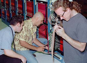 Gordon McGregor (left) and Richard Van de Water of Los Alamos examine MiniBooNE electronics with Morgan Wascko of Louisiana State University