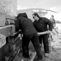 Fermilab technicians Craig Lerette (left) and Steve Sorenson pump oil from a tank truck into the MiniBooNE detector, located inside the building in the background. It will take aoubt 45 truckloads to fill the 250,000-gallon detector tank.