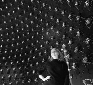 The array of photomultiplier tubes in the MiniBooNE detector provides a backdrop for Lederman Fellow Bonnie Fleming.