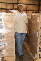 Keith Coiley of Computing Division lends a sense of scale to stacks of repacked and shrink-wrapped PCs.