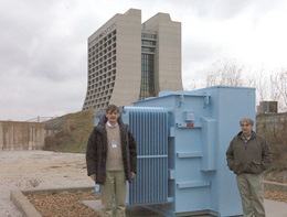 Steve Geer (left), cospokesperson of the Muon collaboration,and construction project manager Milorad Popovic lend a sense of scale to the first components for the new MuCool accelerator R&D lab at Fermilab.Northwestern University donated a transformer (center), and Fermilab built the first part of a beam enclosure in 2000 (left,in background).