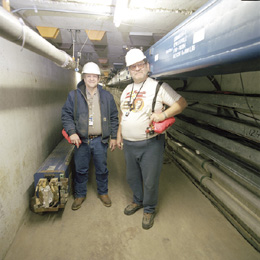 A 2.5-kilometer beam line guides 120 GeV protons from the Main Injector accelerator to the new Meson Test Beam Facility. Paul Feyereisen (left) and Jim Holub were among the technicians who installed renovated magnets to direct the beam through already existing tunnels.